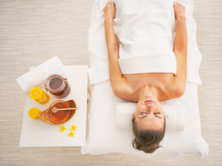Obraz na płótnie Canvas Woman laying on massage table near honey spa therapy ingredients