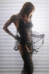 Eine Frau in Dessous hinter Jalousie