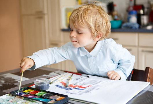 Adorable boy of two years drawing with paints.