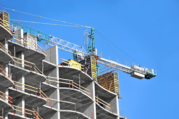 Crane and building construction site against blue sky
