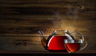 glass teapot with black tea on wooden background