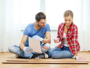 smiling couple measuring wood flooring