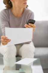 Closeup on young woman holding letter and phone