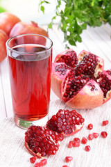 Ripe pomegranates with juice on table on light background