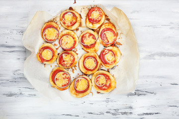 Small pizzas on baking paper on wooden table