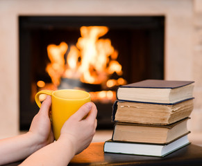 hands holding cup of coffee near the fireplace