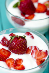 Bowls of strawberry smoothie on vibrant wooden table.