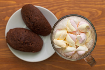 Cocoa with marshmallows and cakes on the table