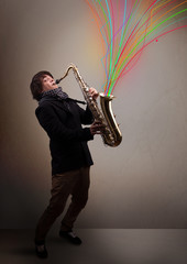 Attractive musician playing on saxophone while colorful abstract
