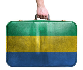 Tourist hand holding vintage leather travel bag with flag of Gab