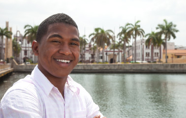 Portrait of a laughing guy with palms and river