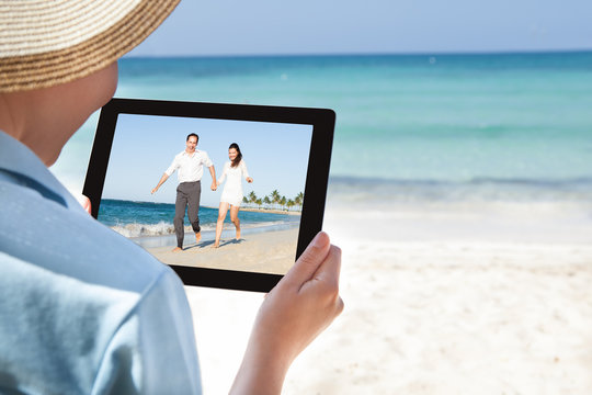 Woman Watching Video On Digital Tablet At Beach