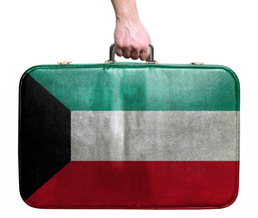 Tourist hand holding vintage leather travel bag with flag of Kuw