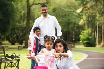indian family teaching their kids cycling in the outdoor park