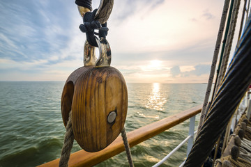 Wooden pulley on an old yacht. Sunset - obrazy, fototapety, plakaty