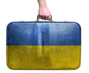 Tourist hand holding vintage leather travel bag with flag of Ukr