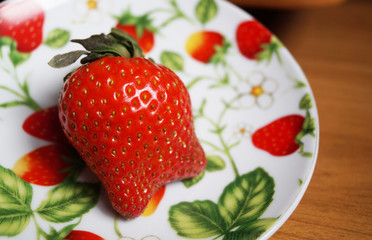 Спелая красная ягода клубники на тарелке