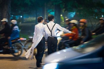 Young couple crossing busy street. Vietnam.