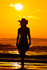 young woman silhouette on the beach in summer