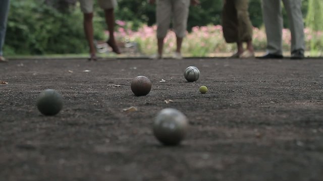 elderly people enjoying to play boules in a park, ball shooting