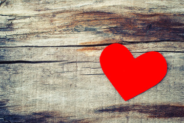 Red paper heart on grunge wooden background