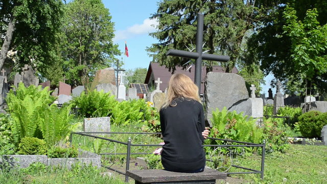 Widow woman near soldier father grave. Lithuania national flag