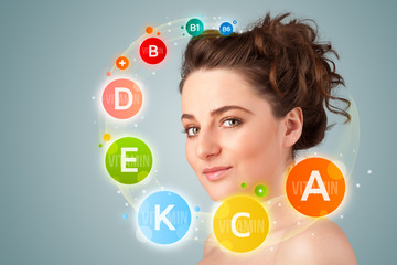 Pretty young girl with colorful vitamin icons and symbols