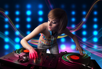 Young Dj girl mixing records with colorful lights