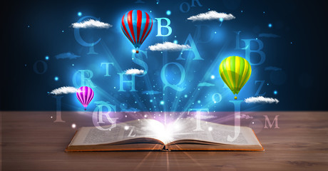 Open book with glowing fantasy abstract clouds and balloons