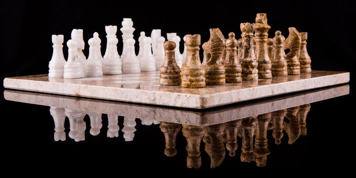 Stone made chess set on black background