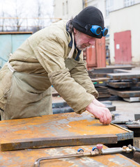 Welder worker measuring and marking steel sheet for cutting