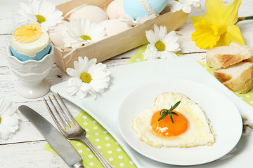 Easter table setting with flowers and eggs on old wooden table