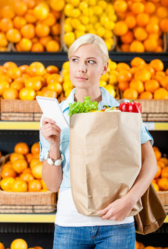 Reading list of products girl hands bag with fresh vegetables 