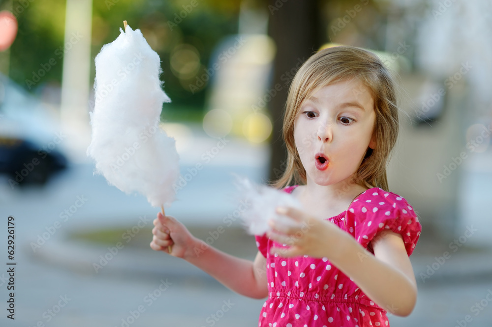 Wall mural adorable little girl eating candy-floss outdoors