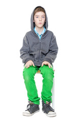 Fototapeta premium upright sitting male teenager on a stool, isolated on white