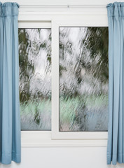 Closed window with curtains in rainy autumn weather