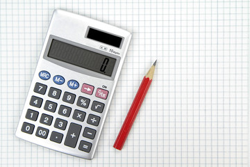 Calculator and lead pencil on squared paper.