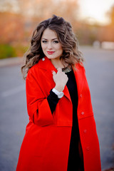 beautiful girl in red coat standing on the road