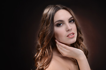 Fototapeta premium Beautiful young woman with long hair on dark brown background