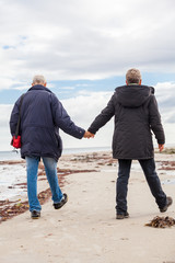 happy elderly senior couple walking on beach