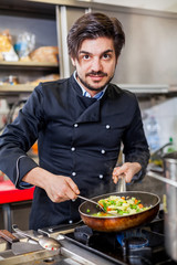 Chef cooking a vegetables stir fry over a hob