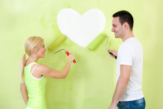 Couple painting heart on wall