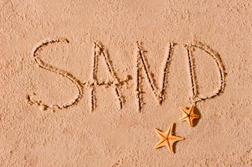 word written on the beach sand and starfish