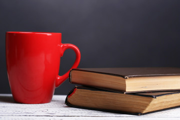 Cup of hot tea with books on table on dark background