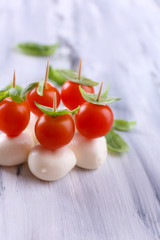 Tasty mozzarella cheese with basil and tomatoes, on wooden