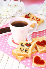 Delicious toast with jam and cup of tea on table close-up