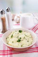 Delicious mashed potatoes with greens in bowl on table close-up