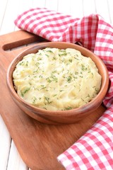 Delicious mashed potatoes with greens in bowl on table close-up