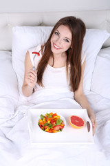 Obraz na płótnie Canvas Young beautiful woman in bed with light breakfast
