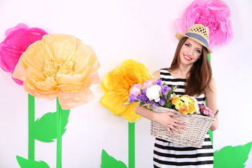 Beautiful young woman holding basket of flowers